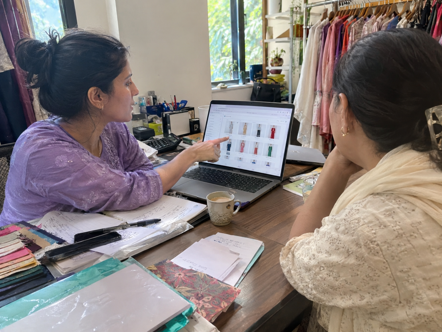 A StyleUAI partner walking a boutique owner through the brand dashboard at her studio desk